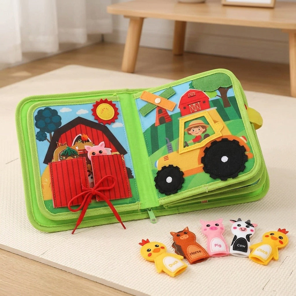 Green fabric busy book opens to barn and tractor activities on a cream floor mat, with animal finger puppets arranged in front.