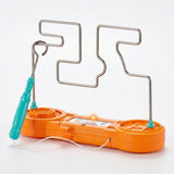 Orange buzz wire game with a turquoise wand loop around the silver-colored track and a glowing light against a white background.