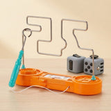 Orange buzz wire game with a turquoise loop wand on a wooden surface, with two gray fidget cubes behind it.