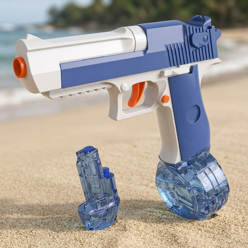 Blue and white toy water gun with orange accents and transparent blue reservoirs displayed on sand against a blurred beach background.