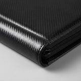Close-up of a black trading card binder shows its textured cover, stitched corner and zipper against a light background.
