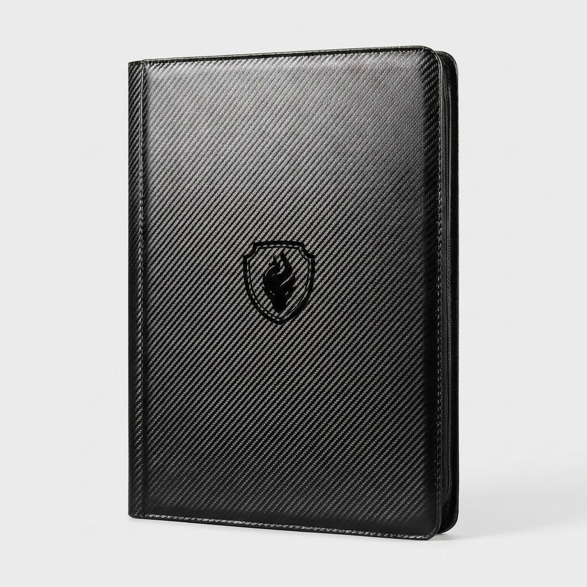 Upright black zippered trading card binder with a carbon fiber textured cover and flame emblem on a plain grey background.