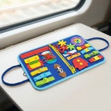 Blue felt busy board with light blue edging lies open on a train table, displaying colorful fasteners, gears and a clock.