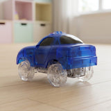 A translucent blue toy car with clear plastic wheels, photographed on a light wood floor in a softly blurred indoor room setting.