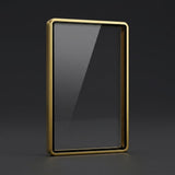 Glossy gold aluminum alloy graded-card protector with a clear center standing upright on a dark gray surface against a dark background.