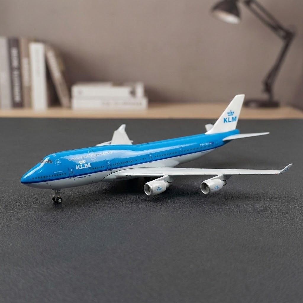 A blue and white aircraft model rests on landing gears on a dark gray surface, with books and a desk lamp behind.