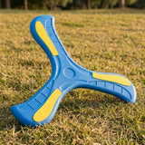 Blue EVA foam boomerang with three curved arms and yellow accents standing on sunlit grass.