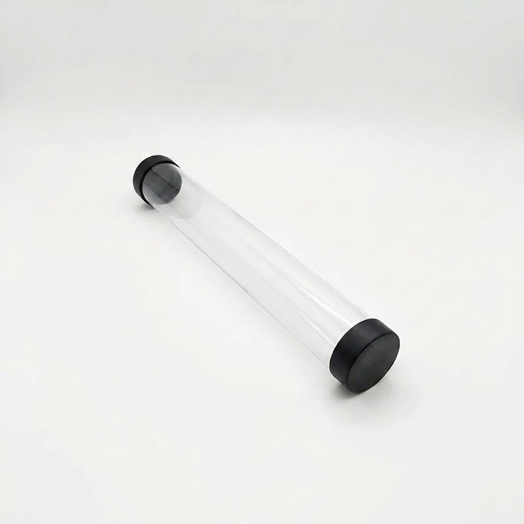 Empty transparent playmat storage tube with black end caps lies diagonally on a white background.