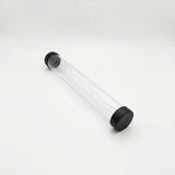 Empty transparent playmat storage tube with black end caps lies diagonally on a white background.