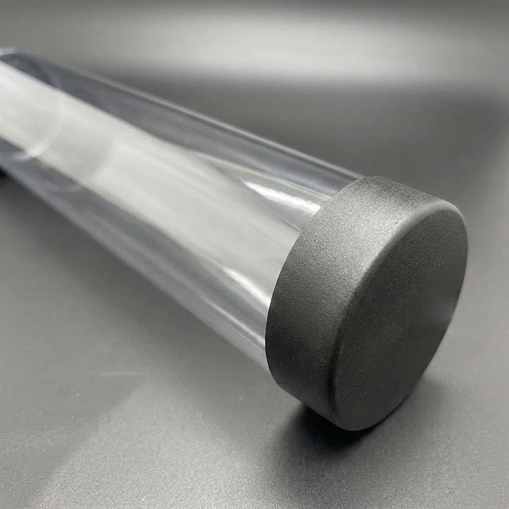 Close-up of a transparent playmat storage tube with a textured black end cap on a dark grey surface.