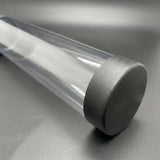 Close-up of a transparent playmat storage tube with a textured black end cap on a dark grey surface.