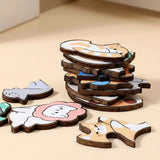 Wooden jigsaw puzzle pieces shaped like colorful cats are stacked and scattered on a beige surface, showing dark cut edges.