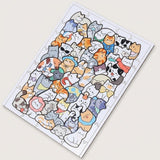 A completed jigsaw puzzle featuring a dense collage of cute cartoon cats in many colors, photographed at an angle on a plain light beige background.