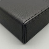 A close-up shows the black deck box’s crosshatched surface, stitched edges, and folded corner against a light gray background.
