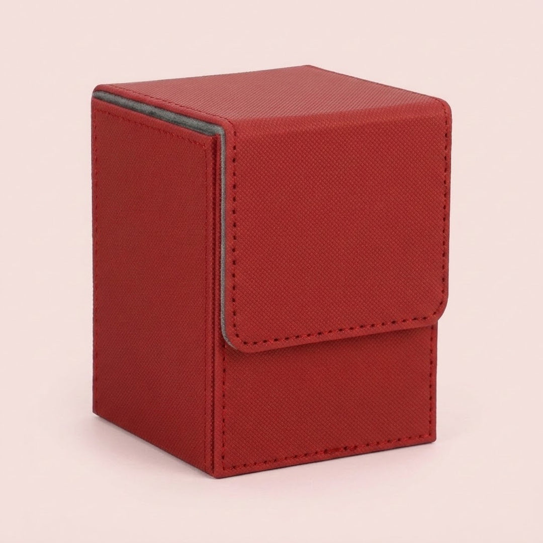 A red textured deck box with stitched edges and a closed fold-over flap stands against a pale pink background.