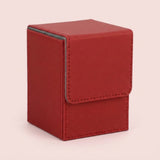 A red textured deck box with stitched edges and a closed fold-over flap stands against a pale pink background.