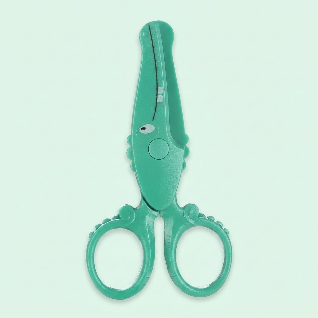 A pair of toddler safety scissors in a bright mint green color, designed with a crocodile head shape and textured handles, shown on a solid pale mint green background.