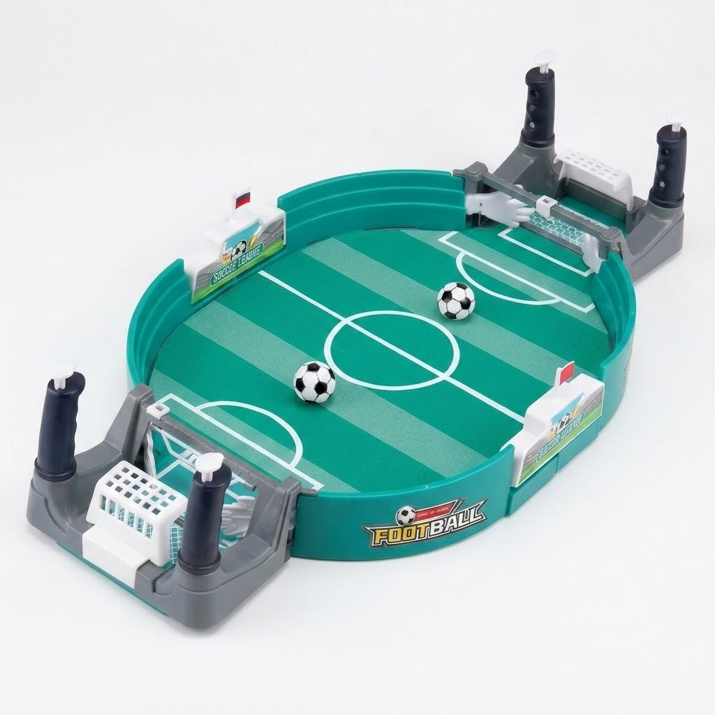 A tabletop soccer game set with a green turf-style field, gray goals, black-and-white soccer balls, and small player figures, photographed on a clean white background.
