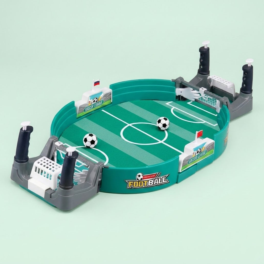Green tabletop soccer game with gray goals, four dark handles, and two balls on the field against a pale mint background.