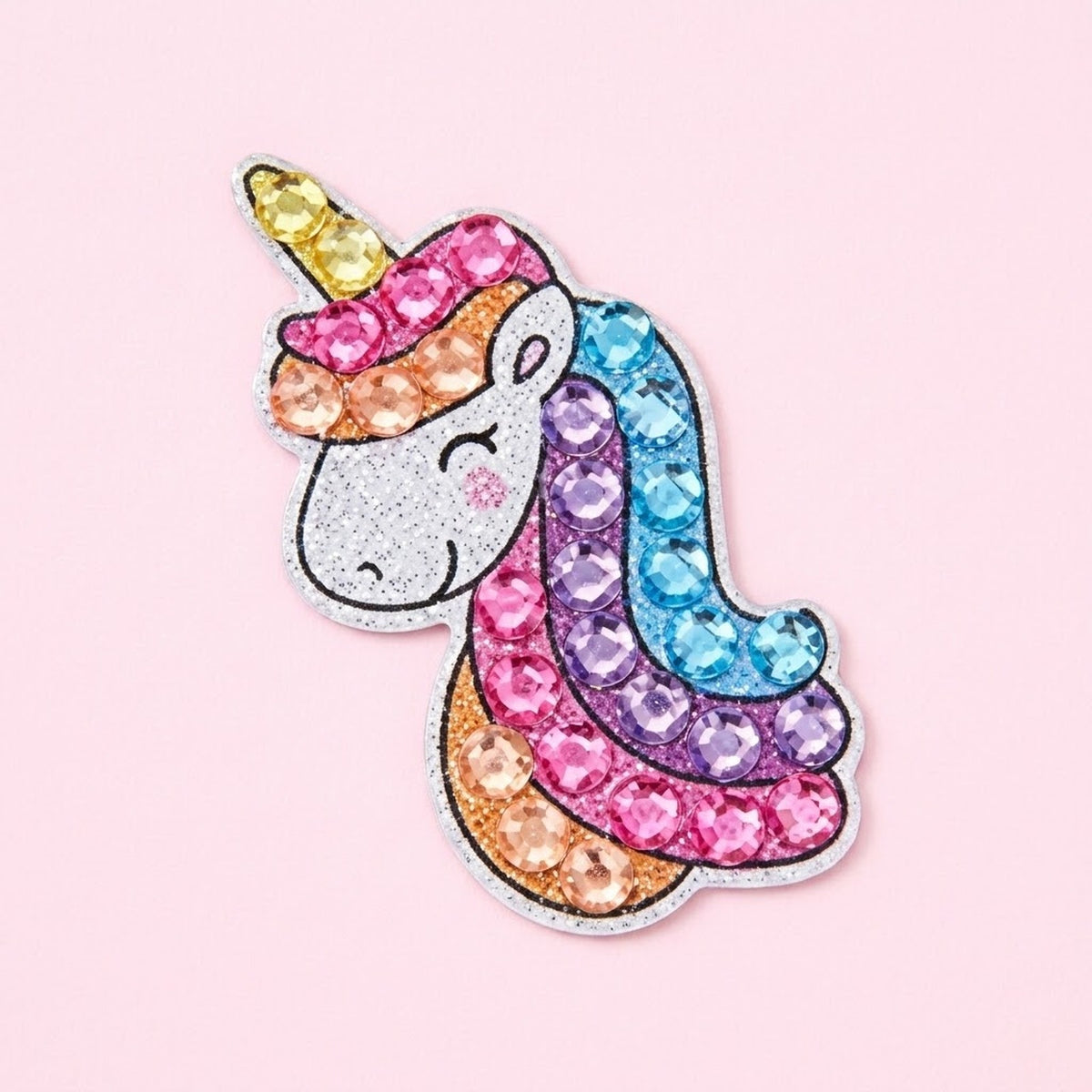 Diamond painting kit unicorn sticker with a silver glitter face and pink, purple and blue gem mane against a pale pink background.