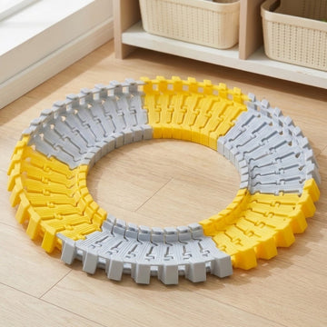 Yellow and light gray plastic race track set forms a circular loop on a wooden floor beside storage baskets.