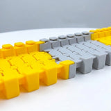 Yellow and light gray plastic race track set shows interlocking joints close up on a white surface against a gray background.