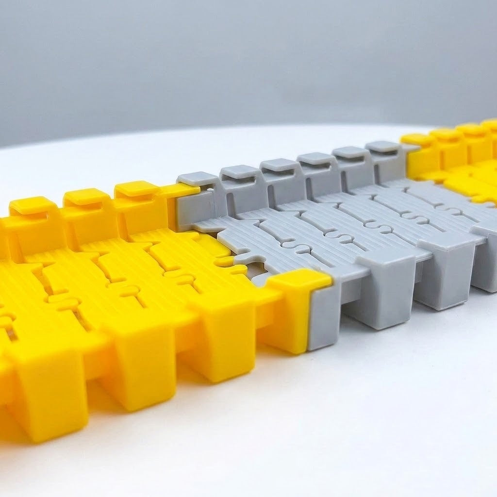 Yellow and light gray plastic race track set shows interlocking joints close up on a white surface against a gray background.