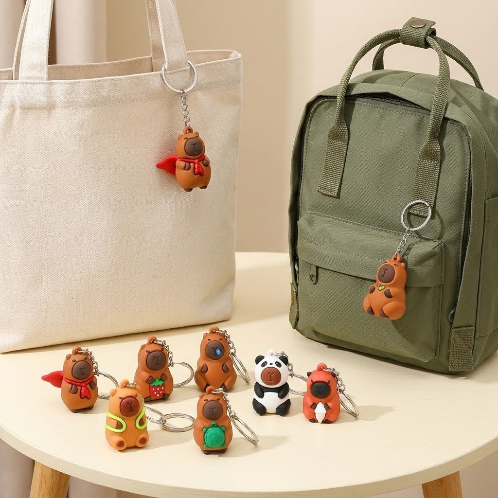 A set of cute cartoon animal keychains displayed on a round table, shown hanging from a cream canvas tote bag and a green backpack, with several keychains arranged in front.