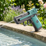 A turquoise-and-grey water gun sprays a stream into a swimming pool from a stone edge, with sunlit flowers behind.