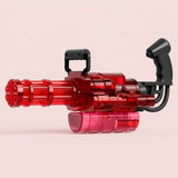 A transparent red electric water gun with black handles and a red lower reservoir stands against a pale pink background.
