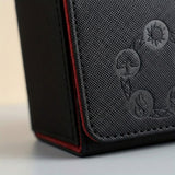 Close-up of a black deck box shows textured PU leather, embossed symbols, stitched edges, and red lining along the flap.