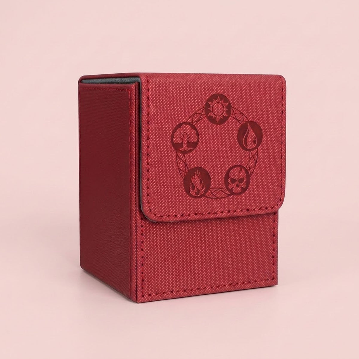 A red textured card deck box with a flap closure featuring a dark red circular emblem of four elemental symbols, set against a solid pale pink background.