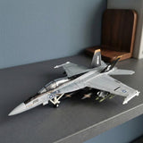 Assembled gray plastic aircraft model kit with black pirate tail fins displayed on a dark shelf beside a blue wall and wooden bookend.