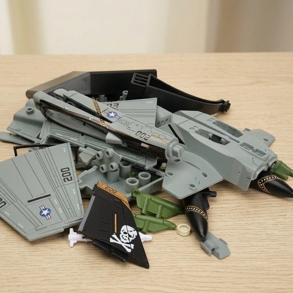 Gray plastic aircraft model kit parts lie on a light wooden tabletop, including black pirate-marked tail fins and green accessories.