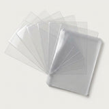 Clear PVC card sleeves fan out beside a neat stack on a light warm gray background.