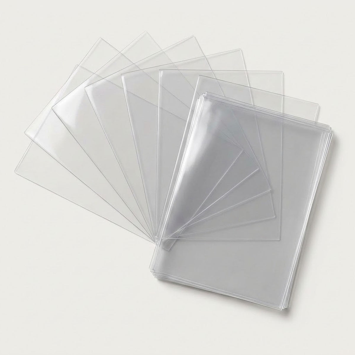 Clear PVC card sleeves fan out beside a neat stack on a light warm gray background.