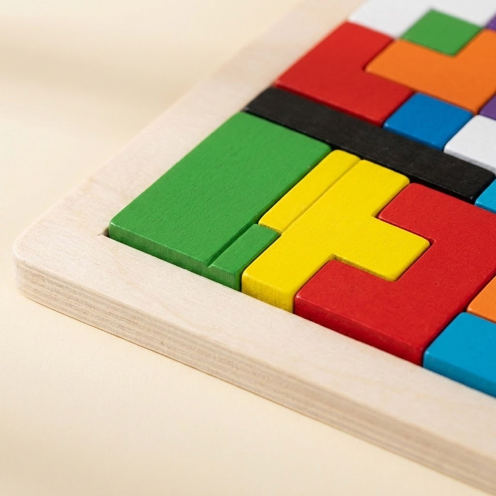 A close-up of the wooden tangram puzzle shows colorful painted blocks fitted inside a pale wood frame on a light surface.