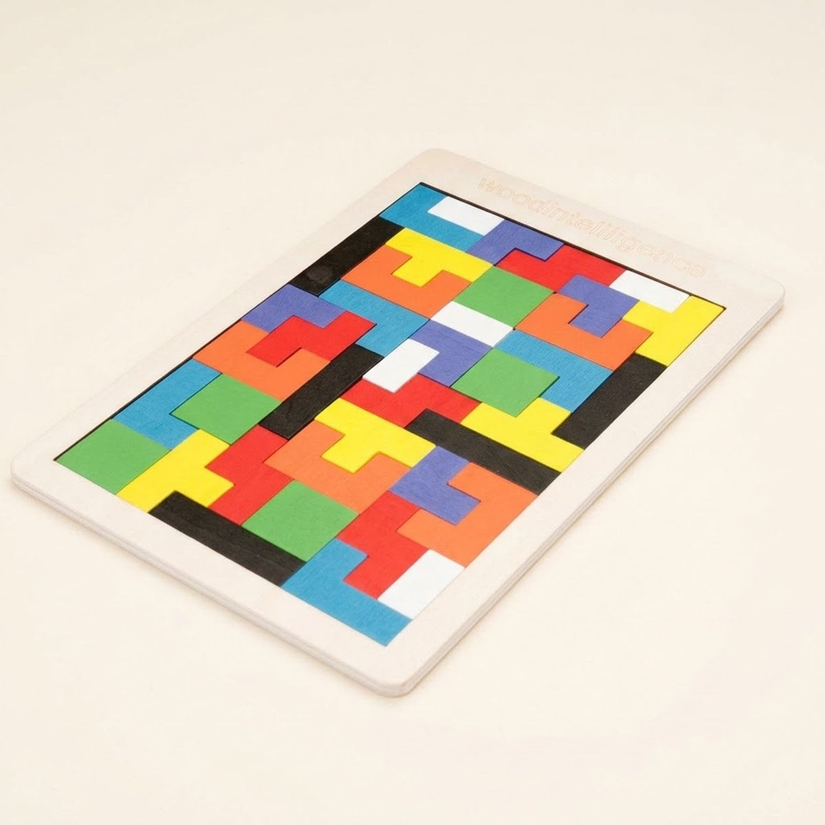 Completed wooden tangram puzzle viewed at an angle on a cream background, with brightly colored geometric pieces inside a pale wooden frame.