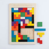 Wooden tangram puzzle viewed from above on white, with four green, blue, yellow and red pieces beside the partially filled board.