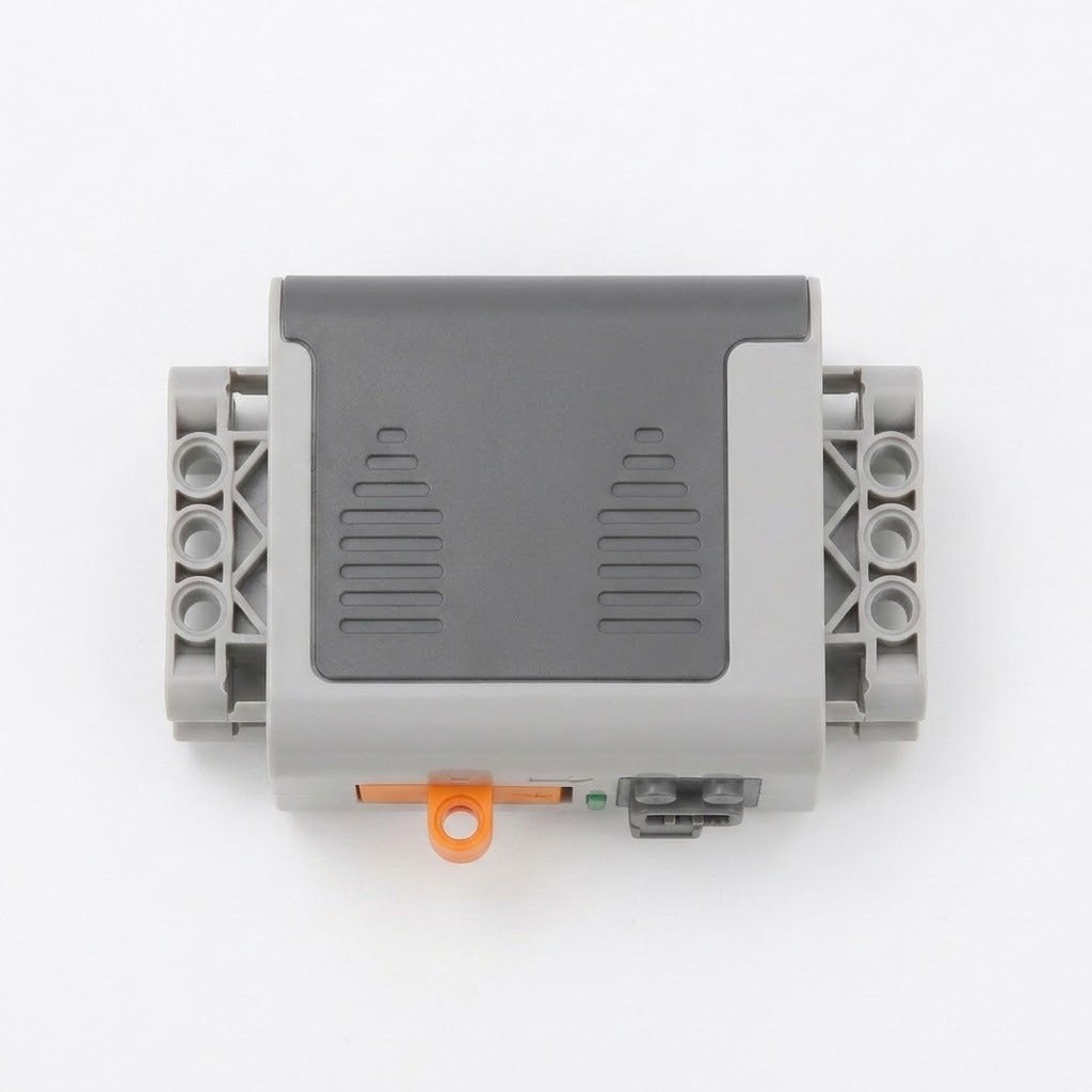 Gray building block accessory battery case with a dark gray cover, orange switch, and side mounting holes rests on a white background.