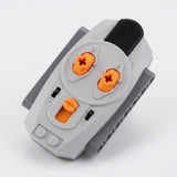 A LEGO Mindstorms brick connector module in gray with bright orange accents and a black tab, photographed on a clean white background.