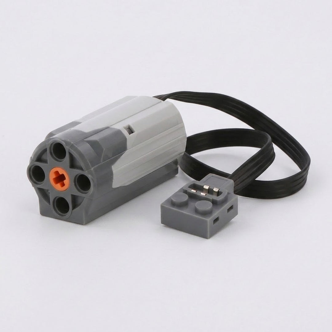 Grey plastic motor accessory for building block sets with an orange centre hub and a flat black cable, photographed on white.