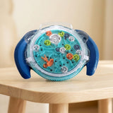 Blue maze puzzle with turquoise tracks and colorful gears stands on a light wooden table against a softly blurred beige background.