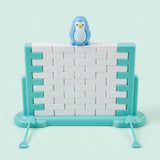 Single-piece penguin balance game with a blue penguin atop a white block wall in a turquoise frame against a pale mint background.