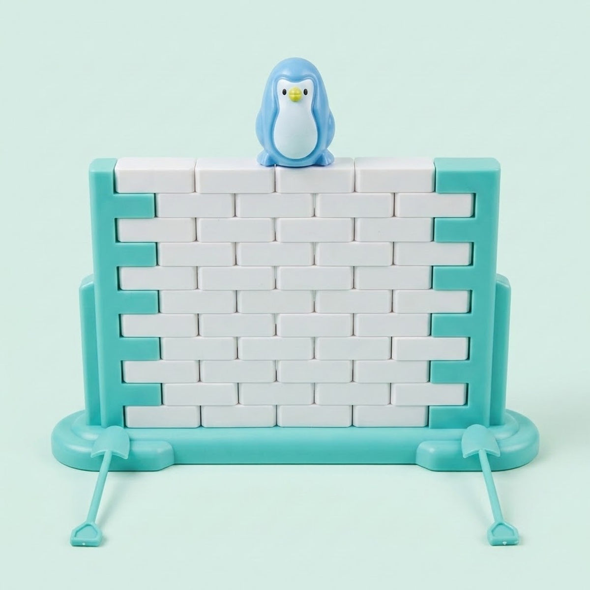 Single-piece penguin balance game with a blue penguin atop a white block wall in a turquoise frame against a pale mint background.