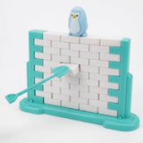 A turquoise tool pushes a white block from the balance game beneath a blue penguin, with a turquoise frame against a white background.
