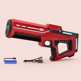 Red and black water gun with pale turquoise accents stands beside a blue battery and USB charging cable against a pale pink background.