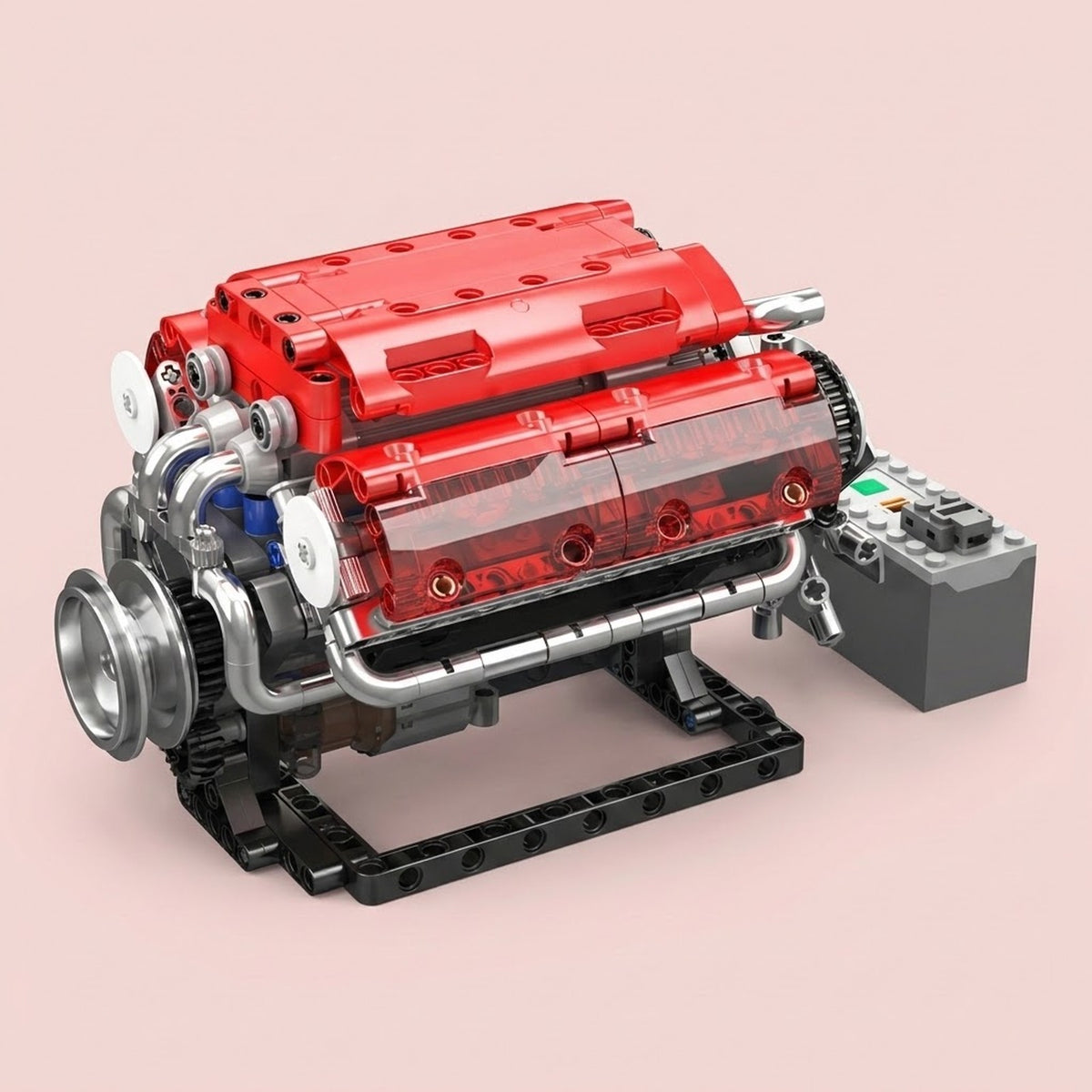 Red plastic V8 engine model kit with silver-colored pipes sits on a black stand beside a gray control box against a pink background.