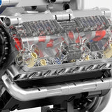 Close-up of the engine model kit shows transparent plastic side panels revealing red and gray internal components above silver-colored pipes.