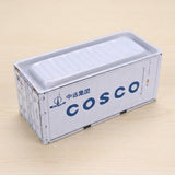 A white metal storage box with navy lettering and a closed lid sits on a pale wooden surface.